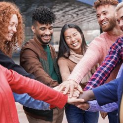 Group of young multiracial people stacking hands outdoor